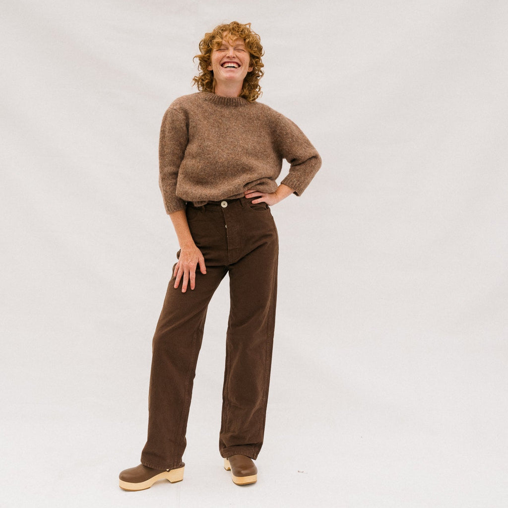 Person wearing a brown sweater and pants on a white background
