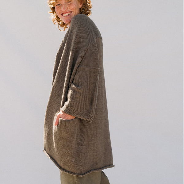 Person wearing a brown sweater against a plain background